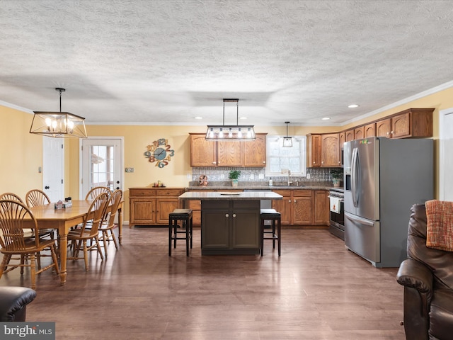 kitchen with pendant lighting, a kitchen island, a wealth of natural light, and appliances with stainless steel finishes