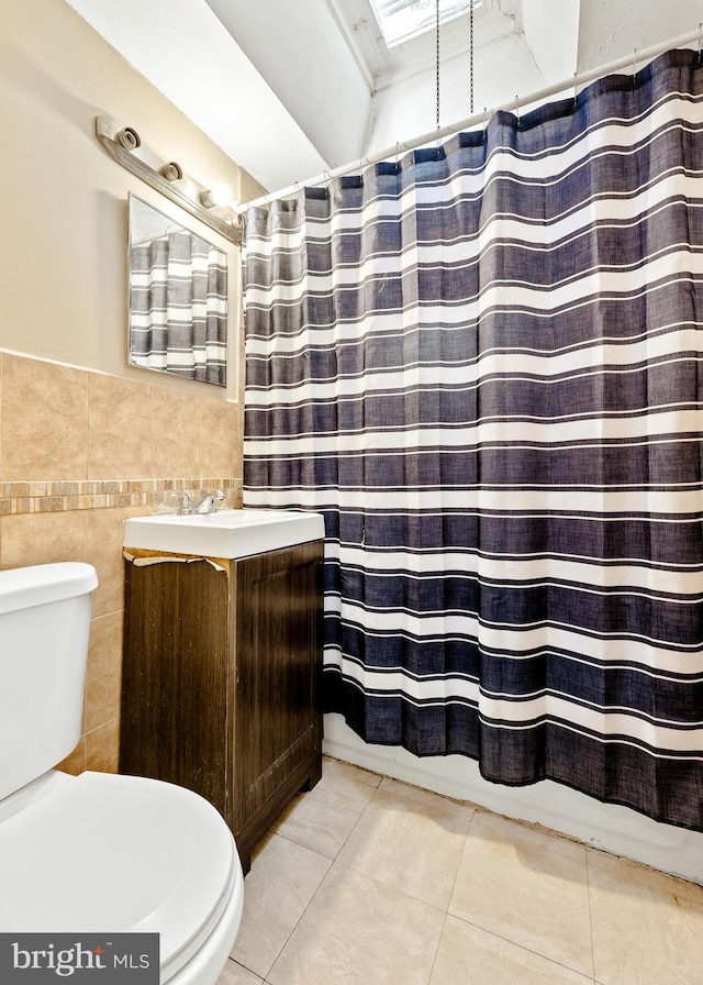 bathroom featuring walk in shower, tile patterned floors, toilet, vanity, and tile walls