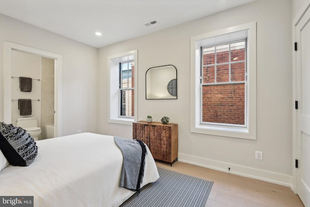 bedroom with ensuite bathroom and light hardwood / wood-style flooring