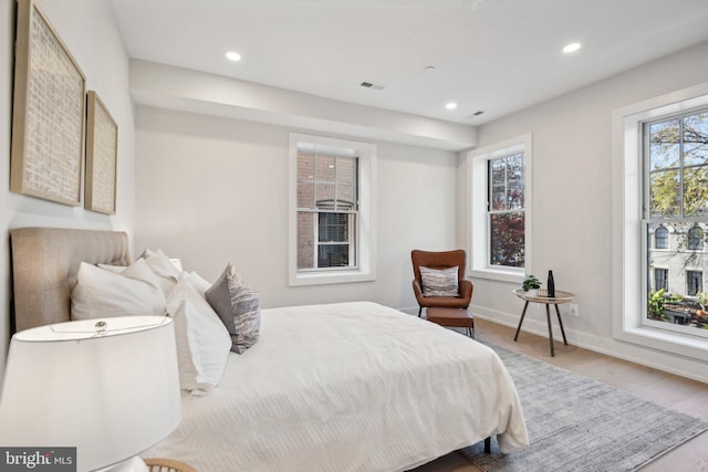 bedroom with multiple windows and light hardwood / wood-style flooring