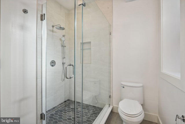 bathroom featuring a shower with shower door and toilet