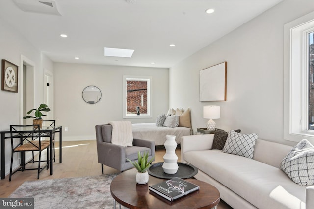 living room featuring plenty of natural light, light hardwood / wood-style floors, and a skylight