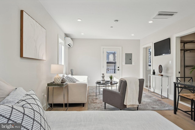 living room with light wood-type flooring, an AC wall unit, and electric panel