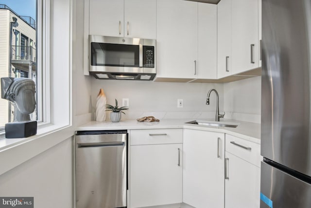 kitchen featuring stainless steel appliances, white cabinetry, and sink