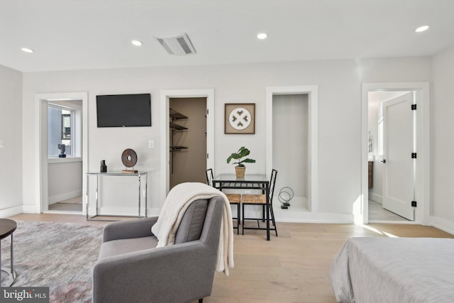 bedroom featuring light wood-type flooring, ensuite bathroom, a spacious closet, and a closet