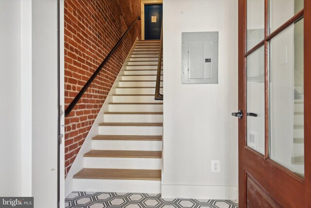 staircase with brick wall and electric panel