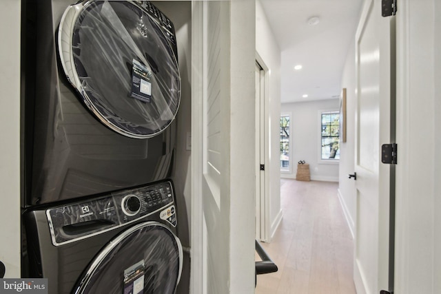 clothes washing area with stacked washing maching and dryer and light hardwood / wood-style floors