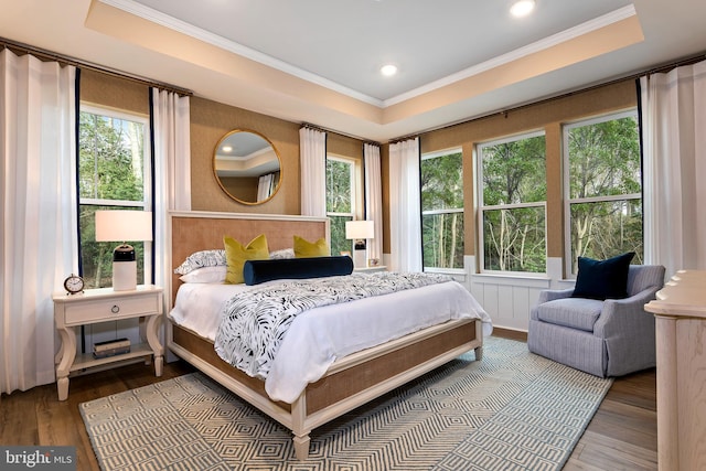 bedroom with ornamental molding, hardwood / wood-style flooring, and a tray ceiling