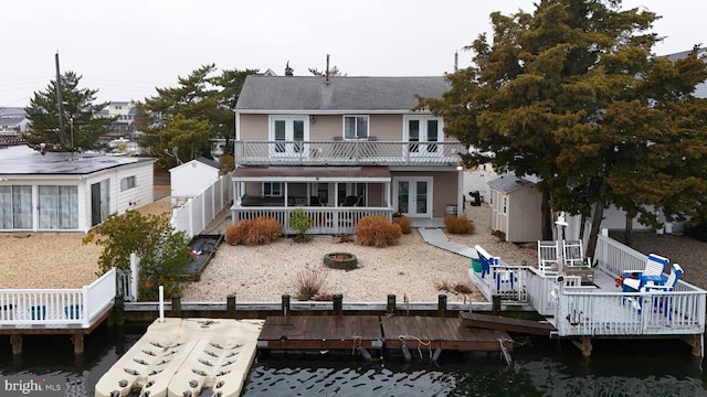 back of house with a fire pit, a storage shed, a deck, and french doors