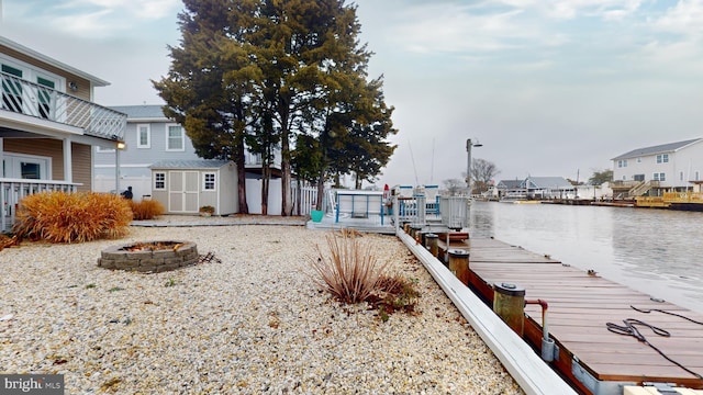 dock area with a deck with water view and an outdoor fire pit