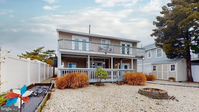 view of front of property featuring a balcony, a fire pit, and a storage unit