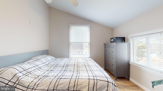 bedroom with ceiling fan, light hardwood / wood-style floors, vaulted ceiling, and multiple windows