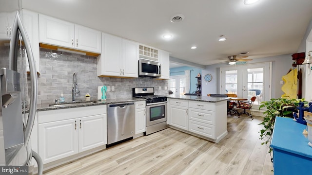 kitchen featuring kitchen peninsula, light wood-type flooring, stainless steel appliances, sink, and white cabinets