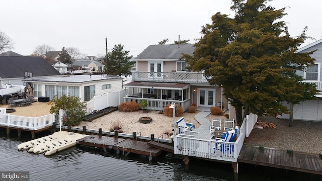 rear view of house with french doors, a deck with water view, and an outdoor fire pit