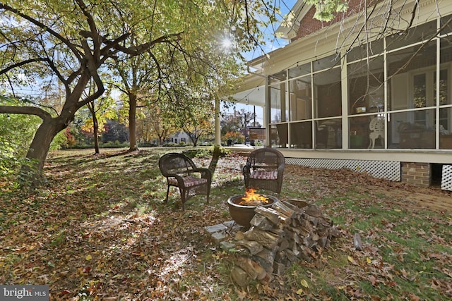 view of yard featuring a fire pit and a sunroom