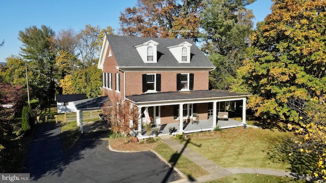 view of front facade featuring a porch, brick siding, and fence