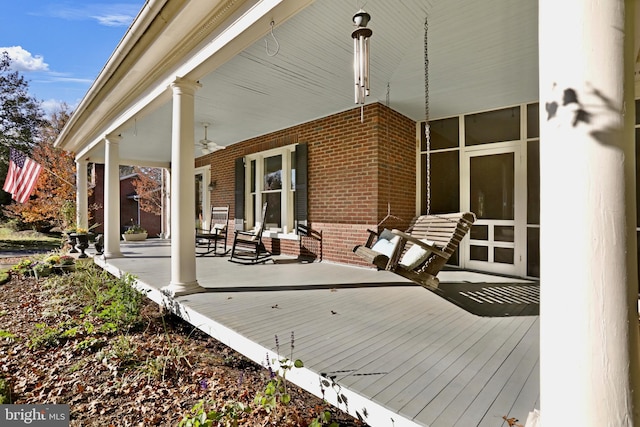 wooden terrace featuring covered porch and a ceiling fan