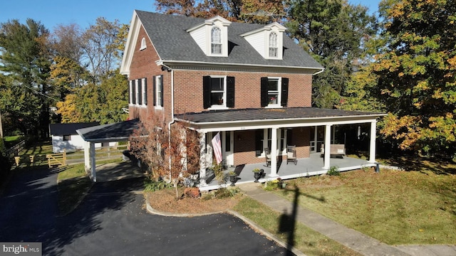 view of front facade featuring covered porch, a carport, brick siding, and a shingled roof