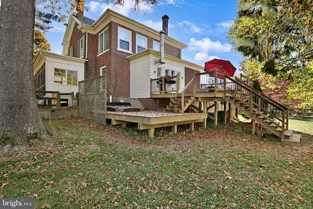 rear view of house featuring stairs, brick siding, and a deck