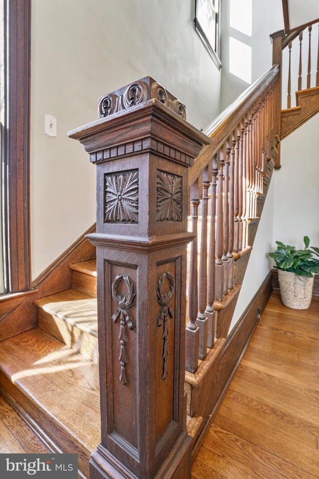 stairway with a high ceiling, wood finished floors, and baseboards