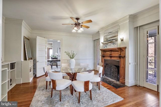 dining room featuring wood finished floors, a wealth of natural light, and crown molding