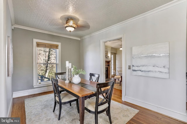 dining space with crown molding, ceiling fan, wood finished floors, and baseboards