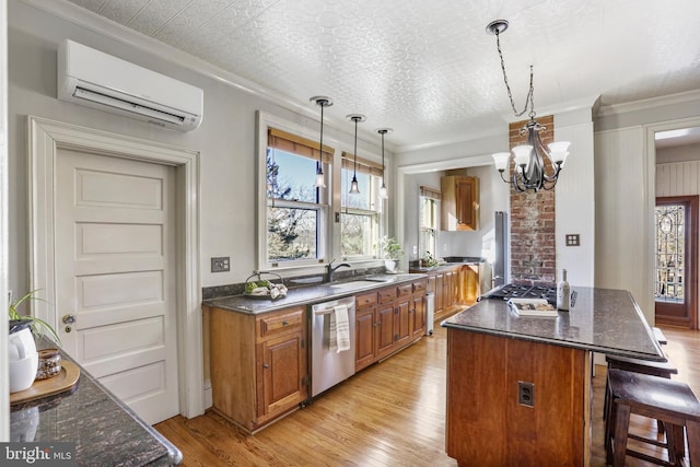 kitchen featuring a wall unit AC, appliances with stainless steel finishes, brown cabinets, and decorative light fixtures