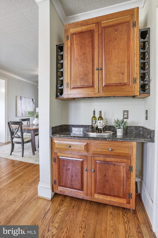 kitchen featuring dark stone counters, brown cabinets, and crown molding