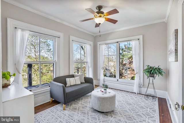 sitting room with a ceiling fan, baseboards, ornamental molding, and wood finished floors