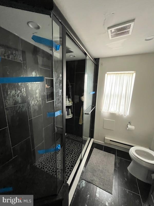 bathroom with tile patterned floors, toilet, a shower with shower door, and a baseboard radiator