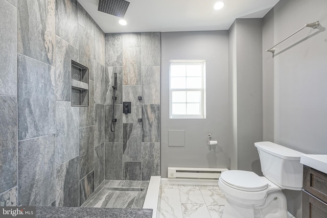 bathroom with a tile shower, vanity, toilet, and a baseboard heating unit