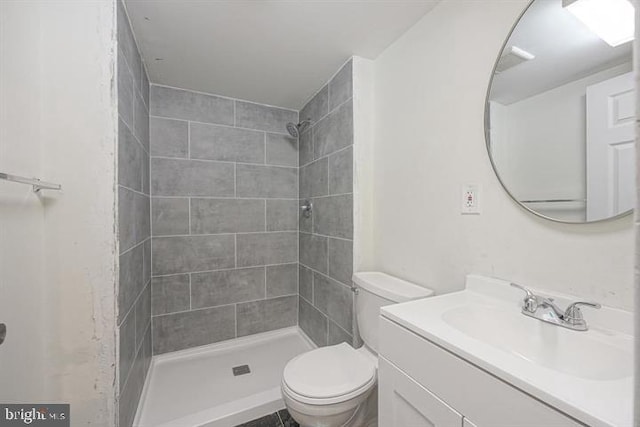 bathroom featuring tiled shower, vanity, and toilet