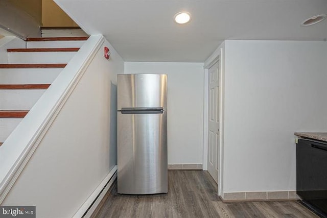 kitchen featuring wood-type flooring, black dishwasher, and stainless steel refrigerator