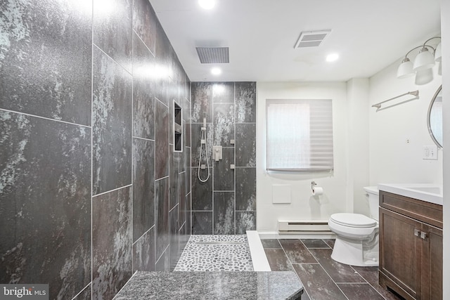 bathroom with a tile shower, vanity, a baseboard radiator, and toilet