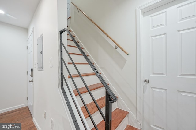 stairs with wood-type flooring and electric panel