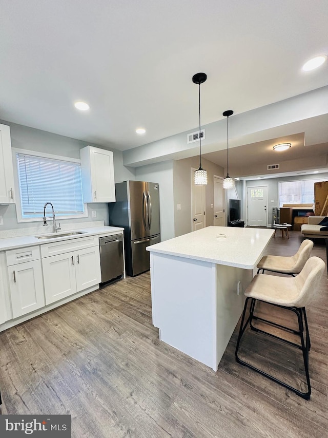 kitchen with white cabinets, appliances with stainless steel finishes, a center island, and sink