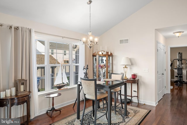 dining space with dark wood-type flooring, lofted ceiling, and a notable chandelier