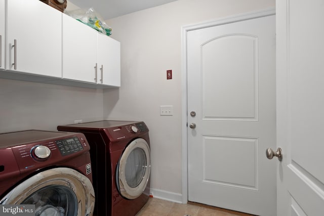 clothes washing area featuring washer and clothes dryer, light tile patterned flooring, and cabinets