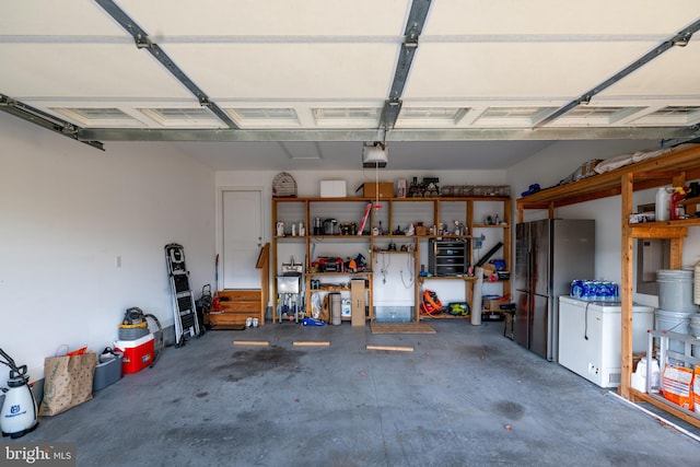 garage with stainless steel fridge and a garage door opener