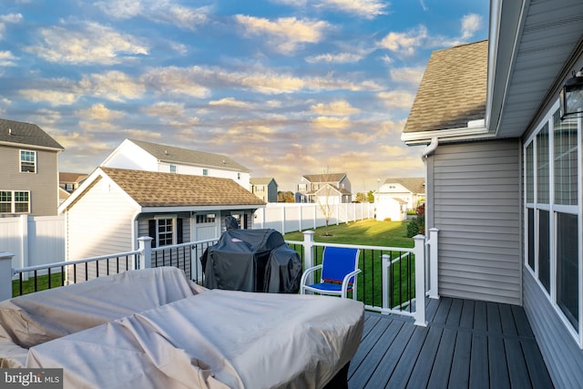 deck at dusk featuring a lawn and area for grilling