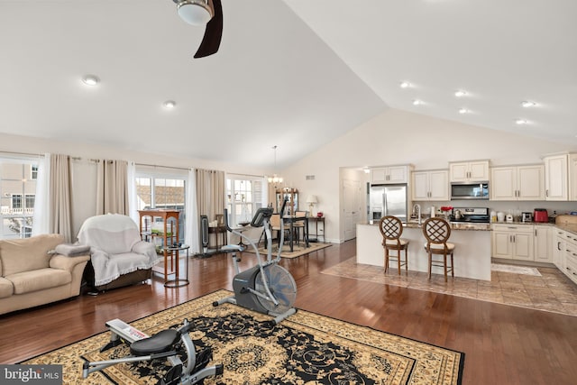 living room with high vaulted ceiling, light hardwood / wood-style floors, and ceiling fan with notable chandelier