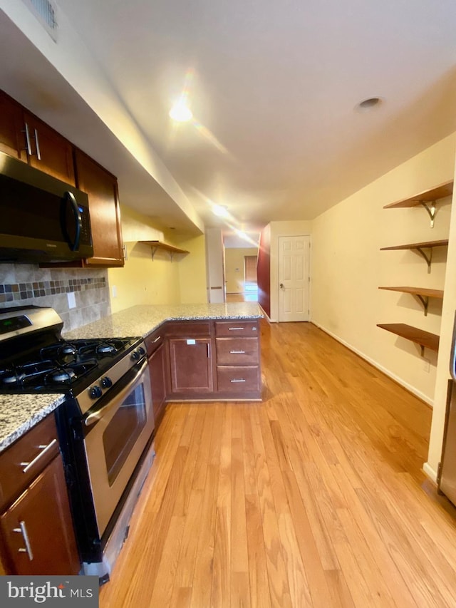 kitchen with decorative backsplash, appliances with stainless steel finishes, kitchen peninsula, light wood-type flooring, and light stone countertops