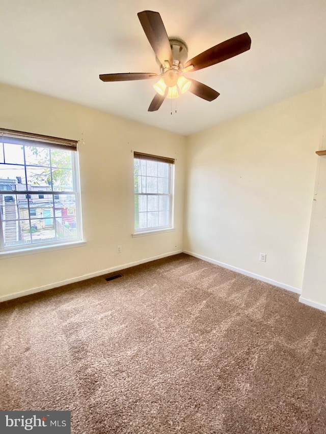 carpeted spare room featuring ceiling fan and a healthy amount of sunlight