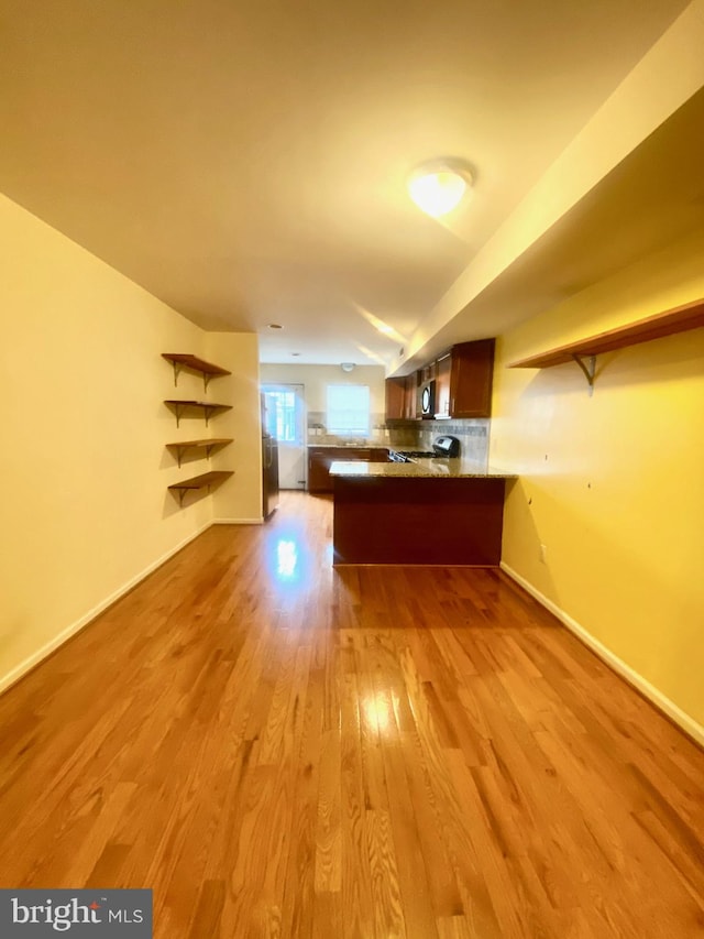 kitchen featuring tasteful backsplash, kitchen peninsula, and light hardwood / wood-style floors