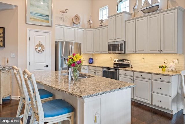 kitchen with stainless steel appliances, white cabinetry, and light stone counters