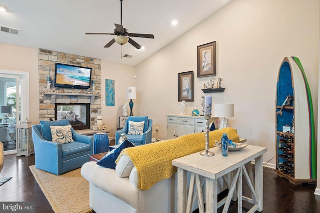 living room featuring ceiling fan, a stone fireplace, wood-type flooring, and vaulted ceiling