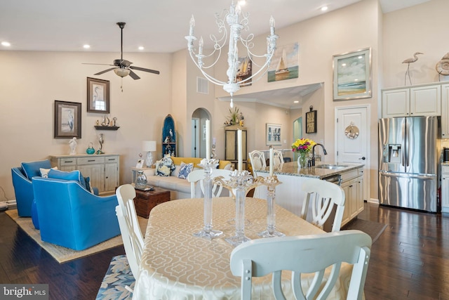 dining area with ceiling fan with notable chandelier, sink, high vaulted ceiling, and dark wood-type flooring