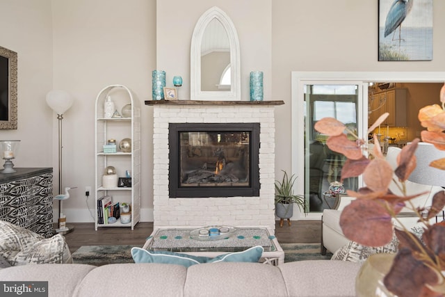 living room featuring dark hardwood / wood-style floors, built in features, and a brick fireplace