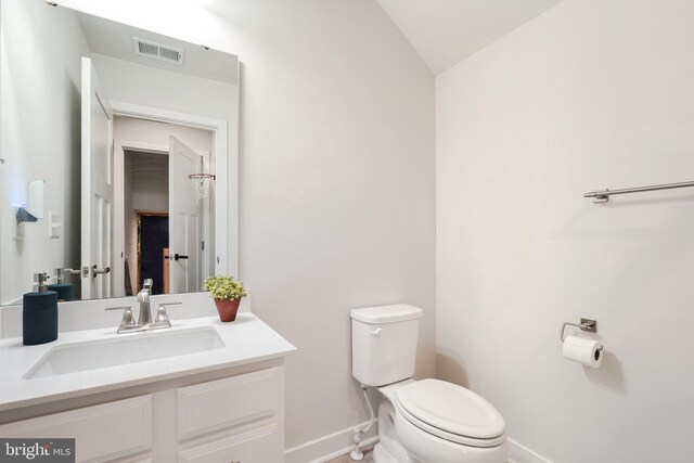 bathroom with toilet, vanity, and vaulted ceiling