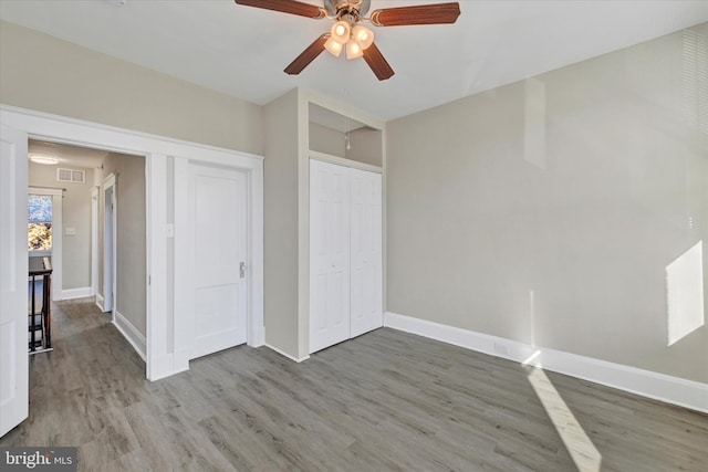 unfurnished bedroom with ceiling fan, wood-type flooring, and a closet